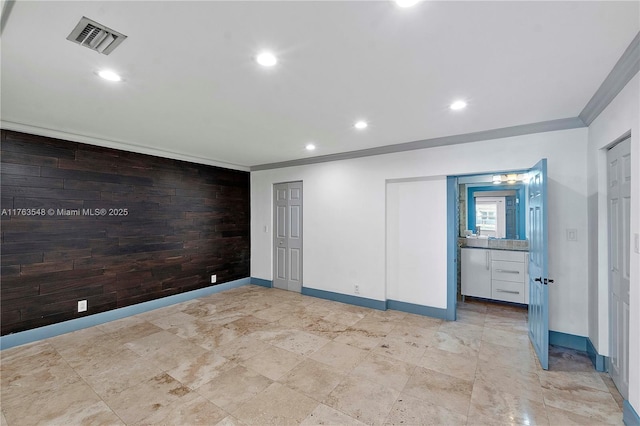 unfurnished room featuring visible vents, wood walls, crown molding, baseboards, and an accent wall