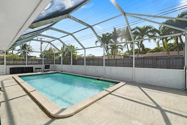 view of swimming pool with glass enclosure, a patio area, and fence