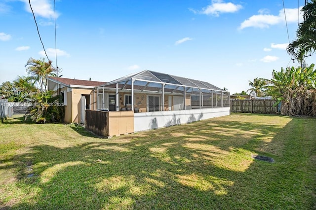 back of property with a lanai, a yard, a fenced backyard, and stucco siding