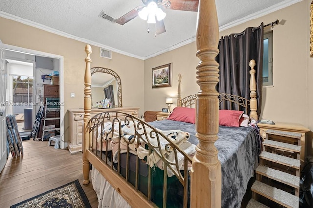 bedroom with visible vents, ornamental molding, a textured ceiling, and wood finished floors