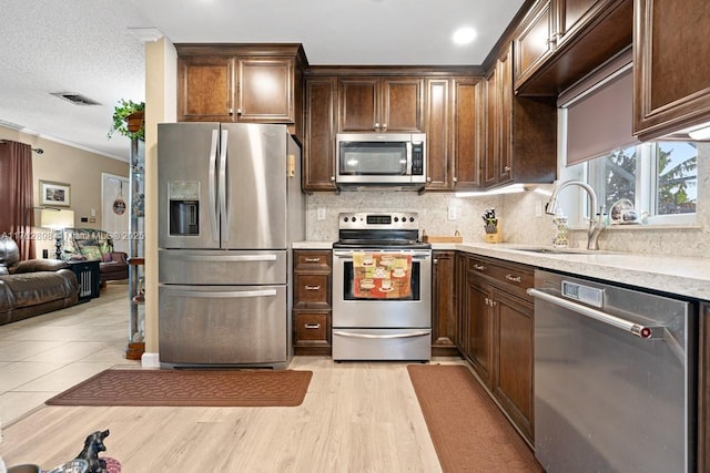 kitchen with dark brown cabinetry, backsplash, appliances with stainless steel finishes, and a sink