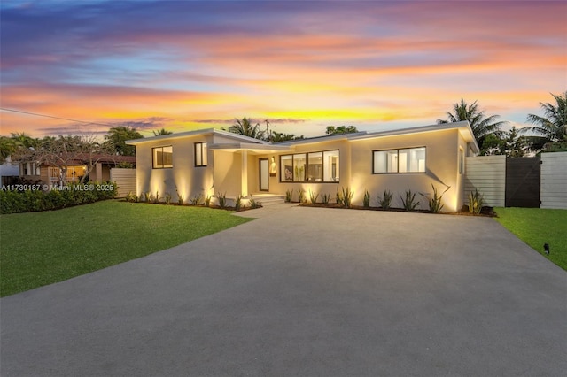 view of front of home with concrete driveway, a lawn, and stucco siding