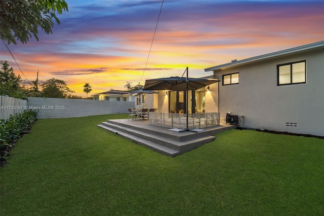 rear view of house featuring stucco siding, a patio, fence private yard, and a yard