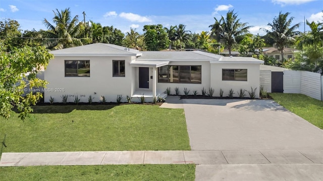 view of front of property with stucco siding, concrete driveway, a front lawn, and fence