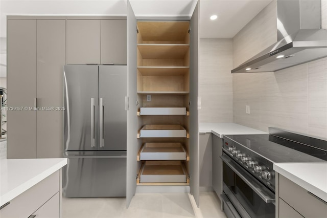 kitchen with light countertops, wall chimney range hood, gray cabinets, and stainless steel appliances