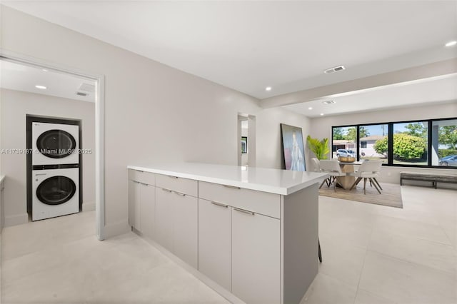 kitchen with visible vents, stacked washer and dryer, modern cabinets, open floor plan, and light countertops