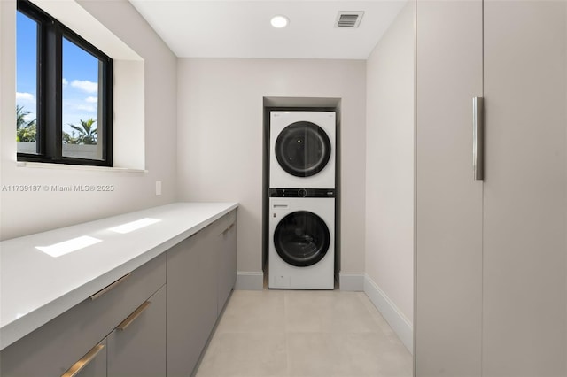 clothes washing area with visible vents, baseboards, recessed lighting, cabinet space, and stacked washer and clothes dryer