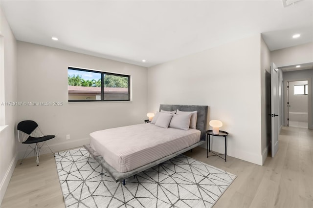 bedroom featuring light wood-style flooring, multiple windows, and baseboards