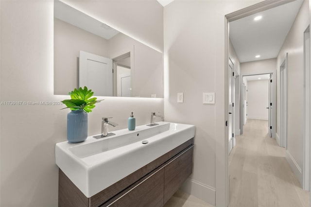 bathroom featuring recessed lighting, baseboards, wood finished floors, and vanity