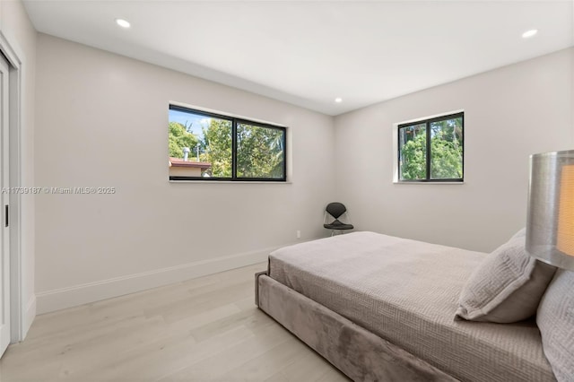 bedroom with recessed lighting, multiple windows, light wood-style floors, and baseboards