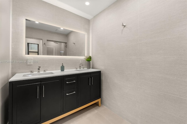 full bathroom featuring a sink, tile walls, double vanity, and tile patterned flooring