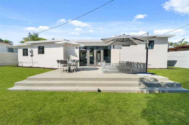 rear view of property with a yard, fence, and stucco siding