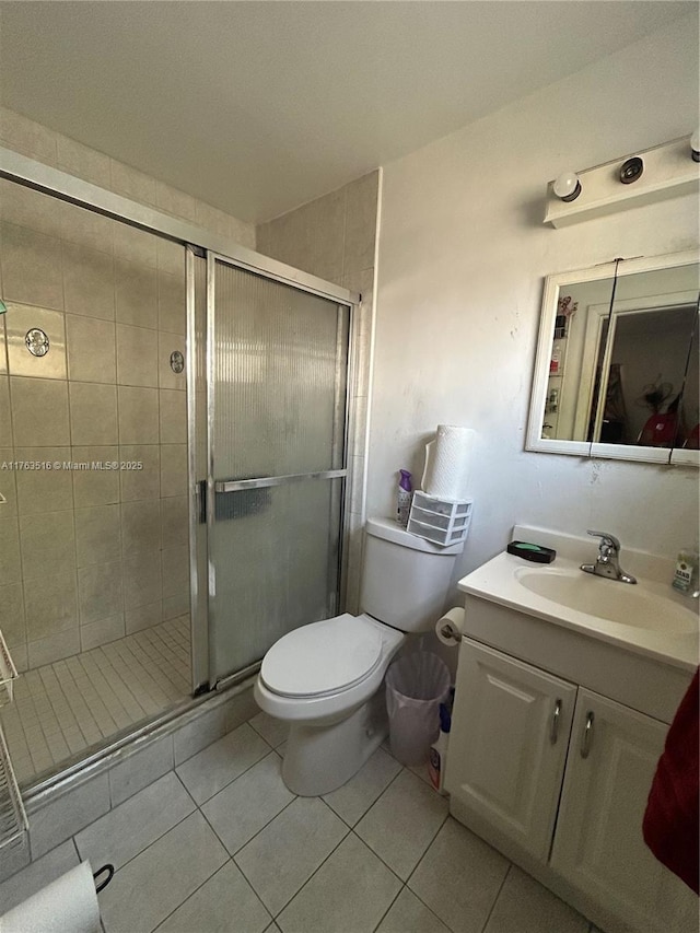 bathroom with tile patterned flooring, a stall shower, toilet, and vanity