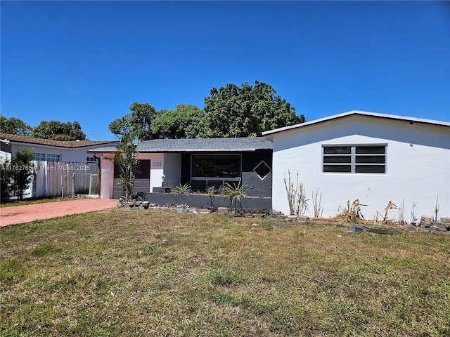 ranch-style home featuring fence, driveway, an attached garage, stucco siding, and a front lawn