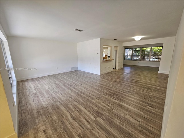 unfurnished living room with visible vents, baseboards, and wood finished floors