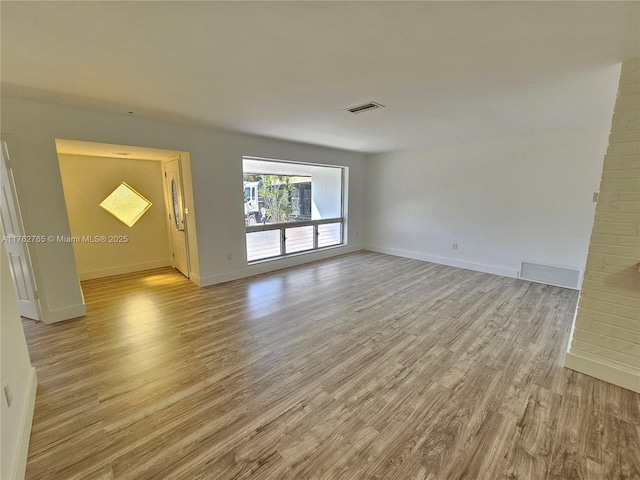 empty room with visible vents, baseboards, and light wood-style floors