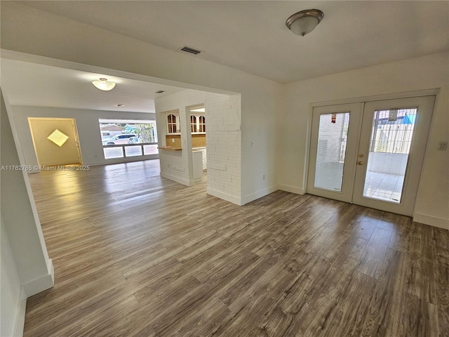 unfurnished room with wood finished floors, visible vents, french doors, and baseboards