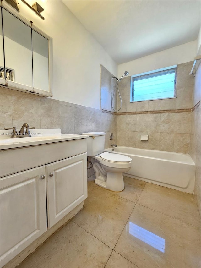 bathroom with vanity, bathtub / shower combination, tile patterned flooring, tile walls, and toilet