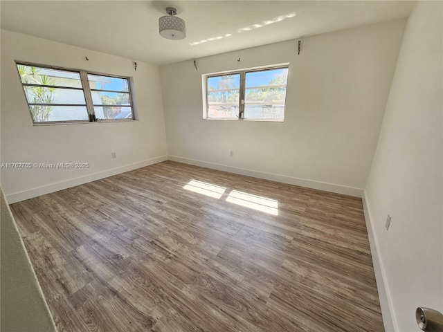 unfurnished room with baseboards and wood finished floors