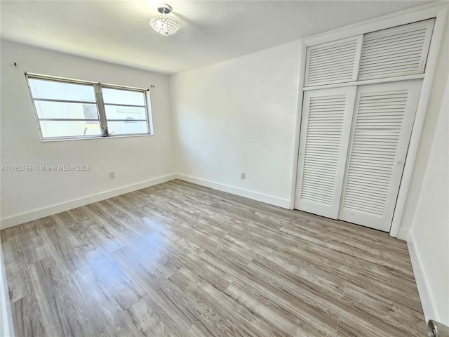 unfurnished bedroom with a closet, baseboards, and wood finished floors