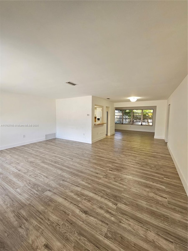 unfurnished living room with wood finished floors, visible vents, and baseboards