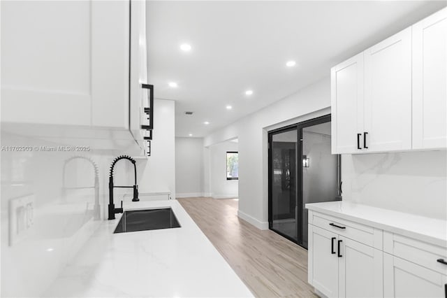 kitchen with a sink, light wood-style flooring, recessed lighting, and white cabinetry