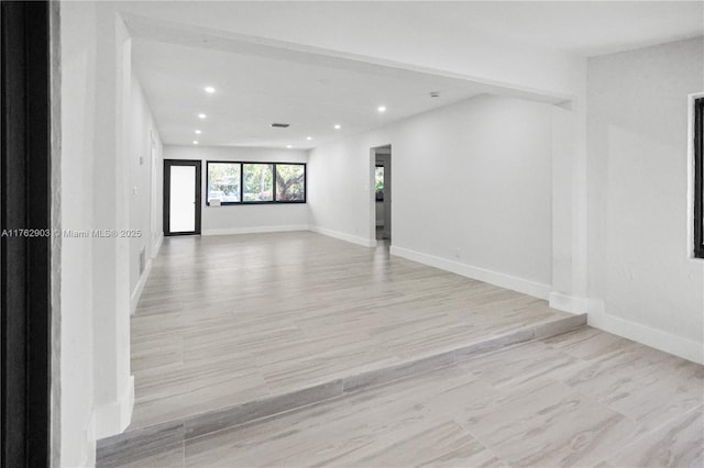 spare room featuring light wood-style floors, recessed lighting, and baseboards