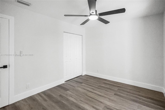 spare room featuring dark wood finished floors, visible vents, baseboards, and ceiling fan