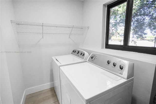 laundry area with laundry area, light wood-style flooring, a wealth of natural light, and washing machine and clothes dryer