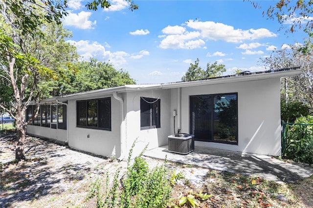 rear view of house with central air condition unit and stucco siding