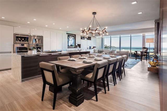 dining area featuring recessed lighting, a water view, light wood-style floors, and a chandelier