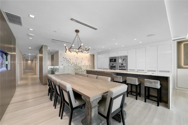 dining space with a chandelier, visible vents, recessed lighting, and light wood-style floors