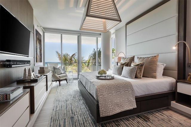 bedroom featuring wood finished floors and floor to ceiling windows