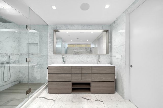 full bathroom featuring a sink, a marble finish shower, tile walls, and double vanity