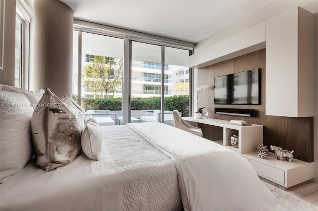 bedroom with a wall of windows, light wood-style flooring, and access to exterior