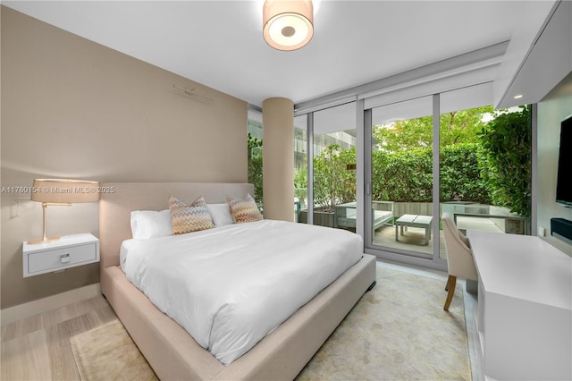 bedroom featuring wood finished floors, floor to ceiling windows, and access to outside