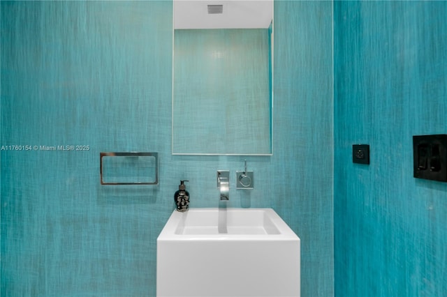 bathroom featuring a bath, visible vents, tile walls, and a sink