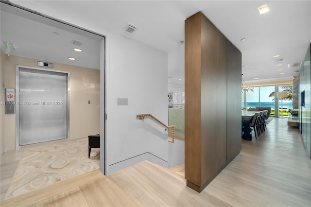 corridor featuring an upstairs landing, visible vents, recessed lighting, and expansive windows