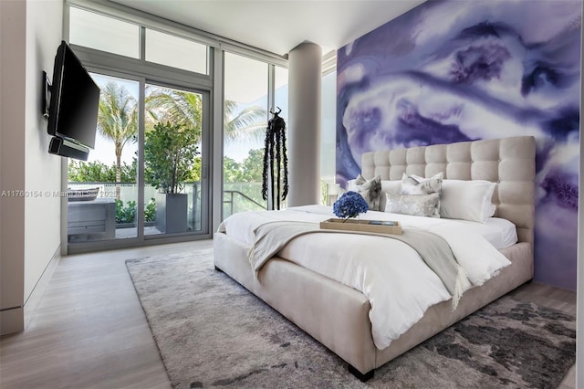 bedroom featuring access to exterior, wood finished floors, and expansive windows