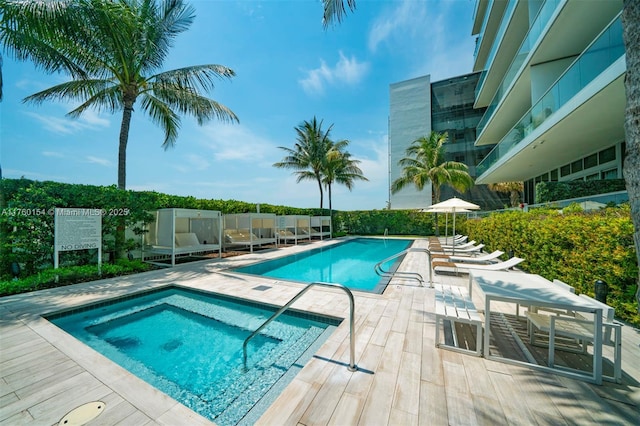 pool with a patio area and a hot tub