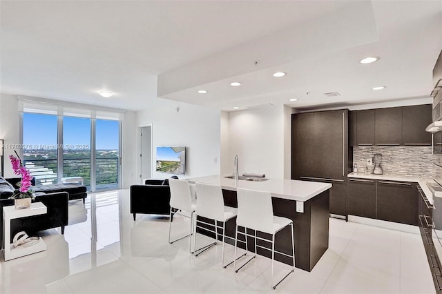 kitchen with tasteful backsplash, open floor plan, a breakfast bar area, light countertops, and modern cabinets