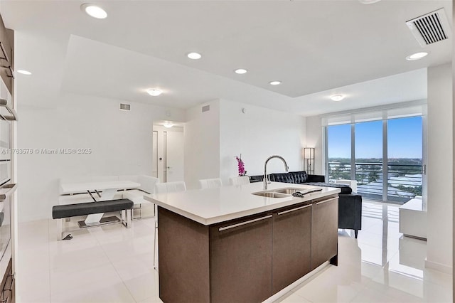 kitchen featuring a center island with sink, recessed lighting, visible vents, and a sink