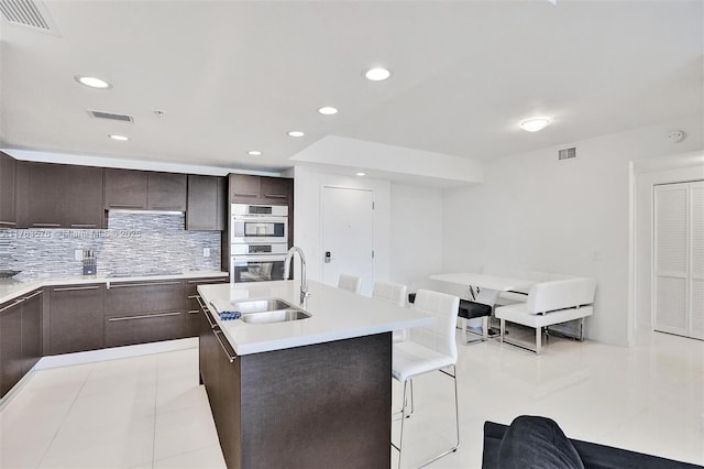 kitchen featuring a sink, visible vents, and dark brown cabinetry