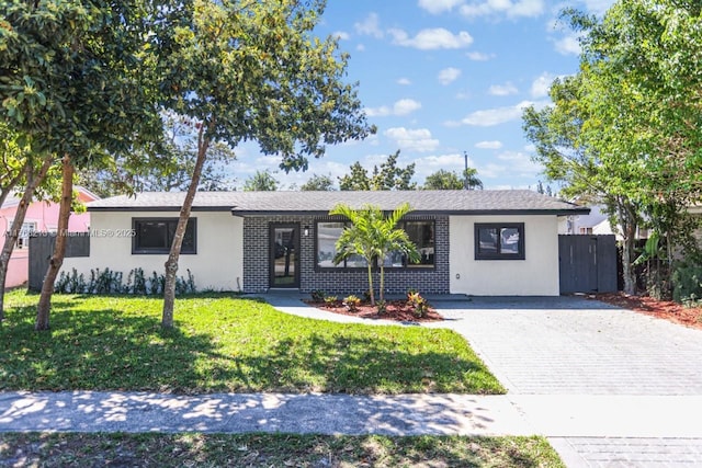 ranch-style home with a front lawn, fence, driveway, and stucco siding