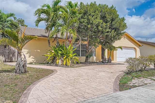 1281 Wyndcliff Dr, Wellington, FL 33414 - view of property hidden behind natural elements with stucco siding, decorative driveway, and a garage
