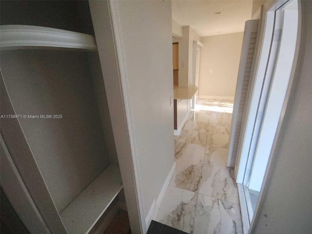 hallway with baseboards and marble finish floor