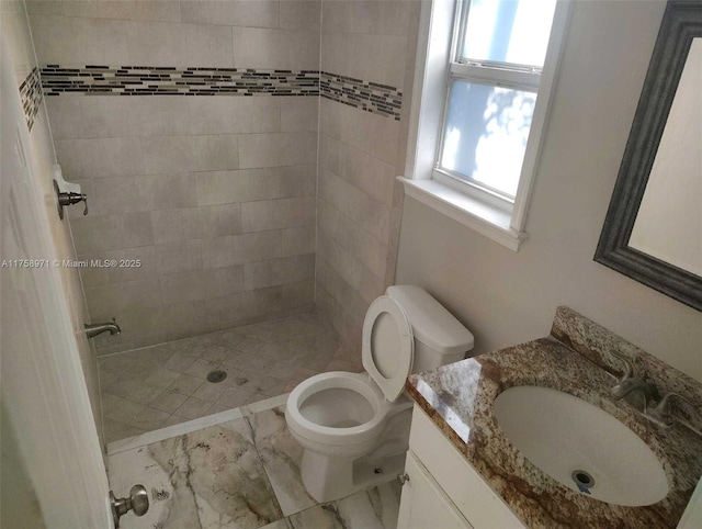 full bath featuring a tile shower, marble finish floor, toilet, and vanity