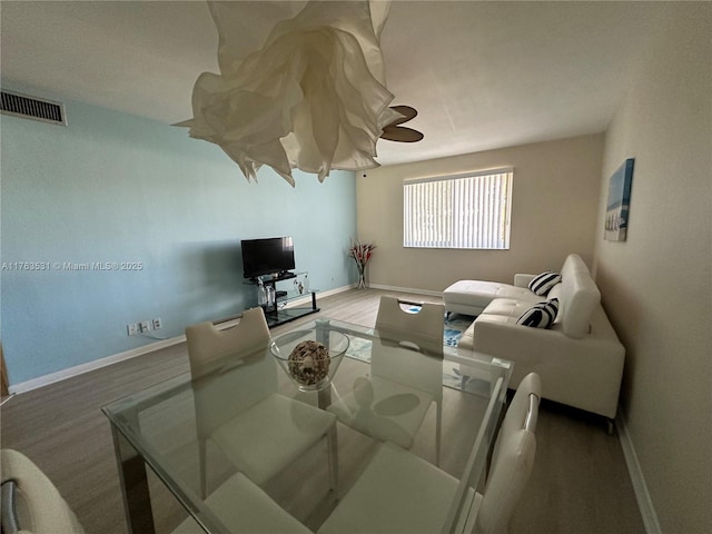 living area with wood finished floors, visible vents, baseboards, and ceiling fan