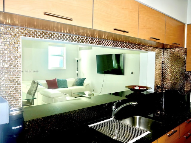 kitchen featuring dark countertops, visible vents, open floor plan, and a sink