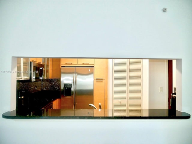 kitchen featuring a peninsula, stainless steel fridge with ice dispenser, glass insert cabinets, dark countertops, and tasteful backsplash